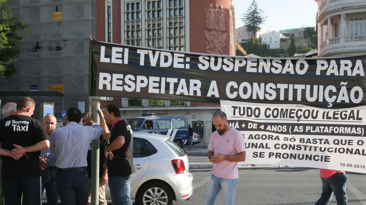 Taxistas reunidos junto a uma faixa com as palavras "Lei TVDE: Suspensão Para Respeitar a Constituição" durante o protesto dos taxistas, em Lisboa.
