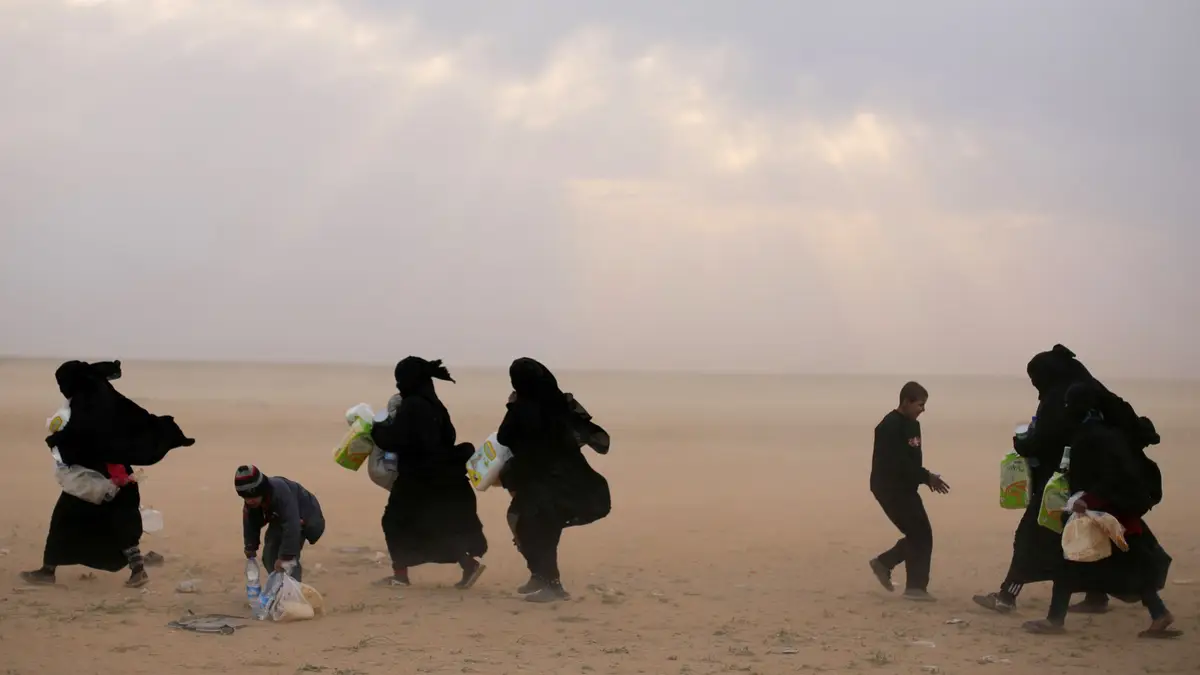 Mulheres fogem da região de Baghouz, na Síria