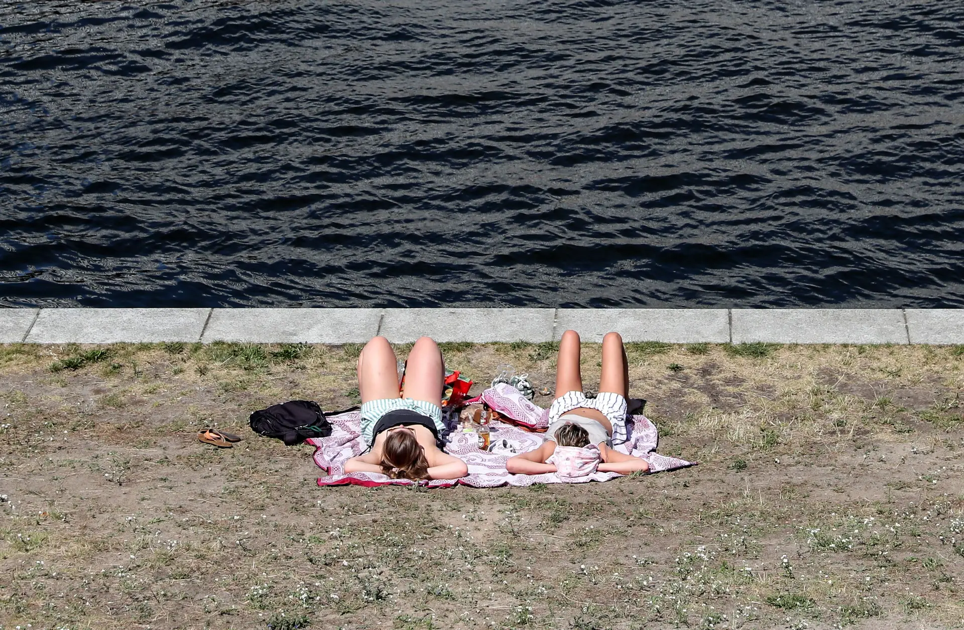 Duas mulheres aproveitam o sol, durante um dia de calor, em Berlim, na Alemanha.  