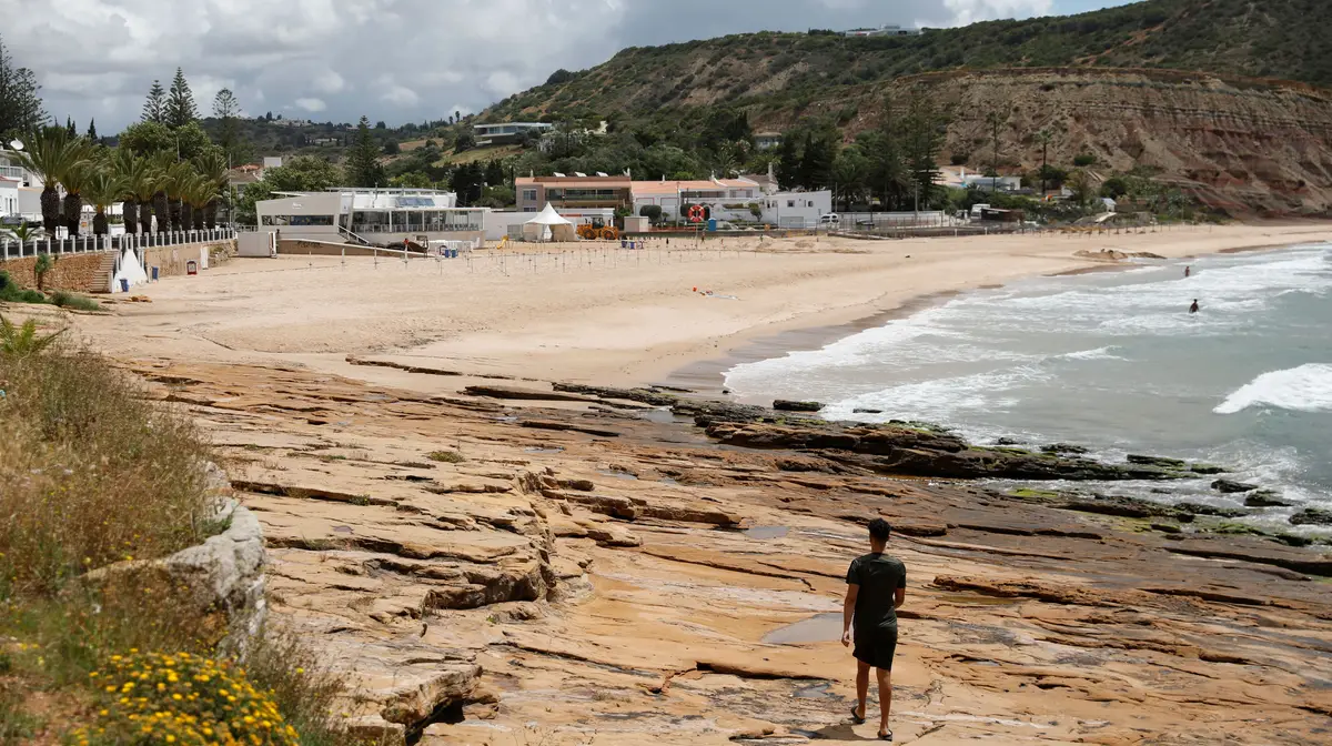 Um homem passeia na praia da Luz, Algarve