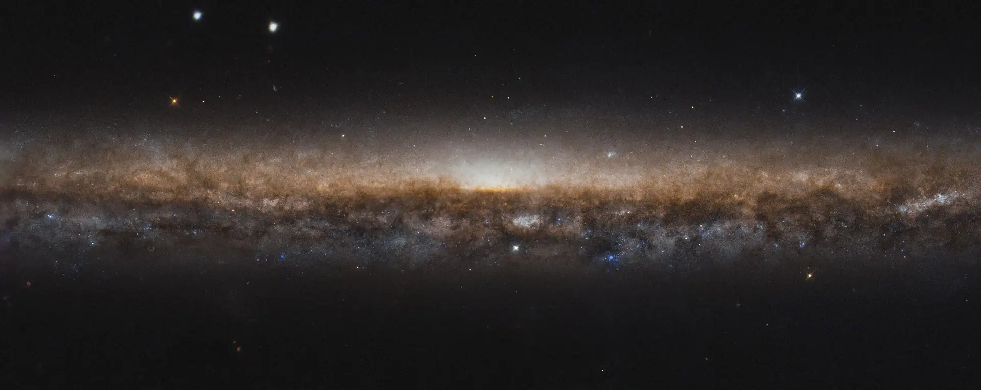 A galáxia NGC 5907, uma linha alongada de estrelas e poeira escura, é uma galáxia espiral, tal como a nossa Via Láctea. Nesta nova imagem captada pelo Telescópio Espacial Hubble da NASA / ESA, não vemos a espiral porque estamos a vê-la alongada, como se estivéssemos a olhar para a borda de um prato. É por essa razão que a NGC 5907 também é conhecida como Galáxia Ponta de Faca (Galaxy Knife Edge). Está a cerca de 50 milhões de anos-luz da Terra, na constelação de Draco. Embora não sejam visíveis nesta imagem, fluxos de estrelas circulam em torno da galáxia; acredita-se que sejam remanescentes de uma pequena galáxia anã, destruída pela Knife Edge e que nela se fundiu há mais de quatro mil milhões de anos.