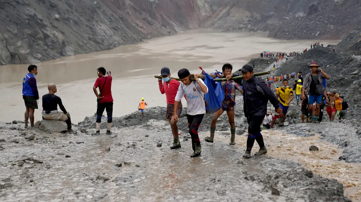 Voluntários carregam uma das vítimas do deslizamento de terras numa mina em Myanmar