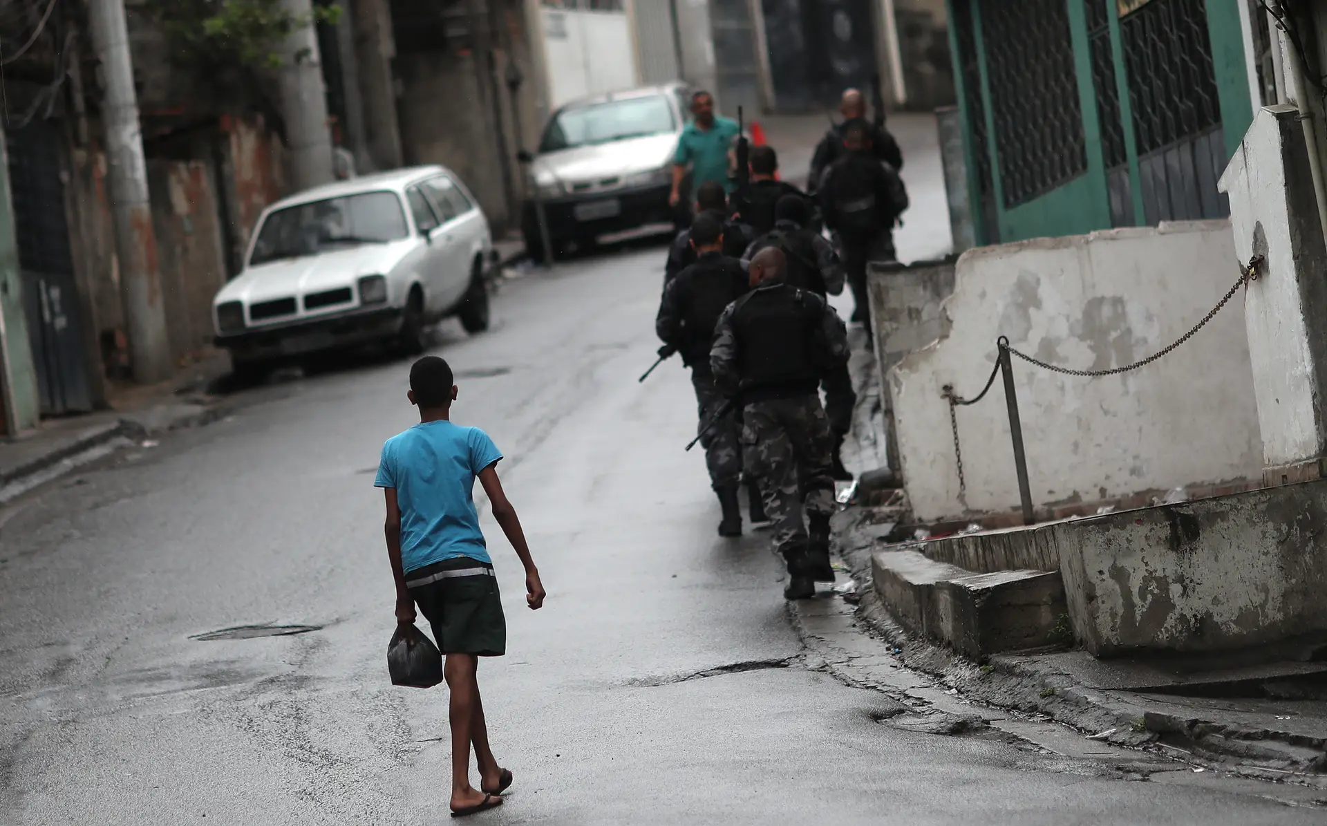 Rapaz observa a Polícia brasileira durante uma patrulha contra o tráfico de droga, numa favela do Rio de Janeiro.