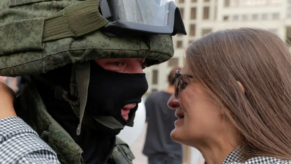 Uma mulher emociona-se e abraça um militar, durante os protestos na Bielorrússia contra os resultados das eleições presidenciais do país e a violência policial.