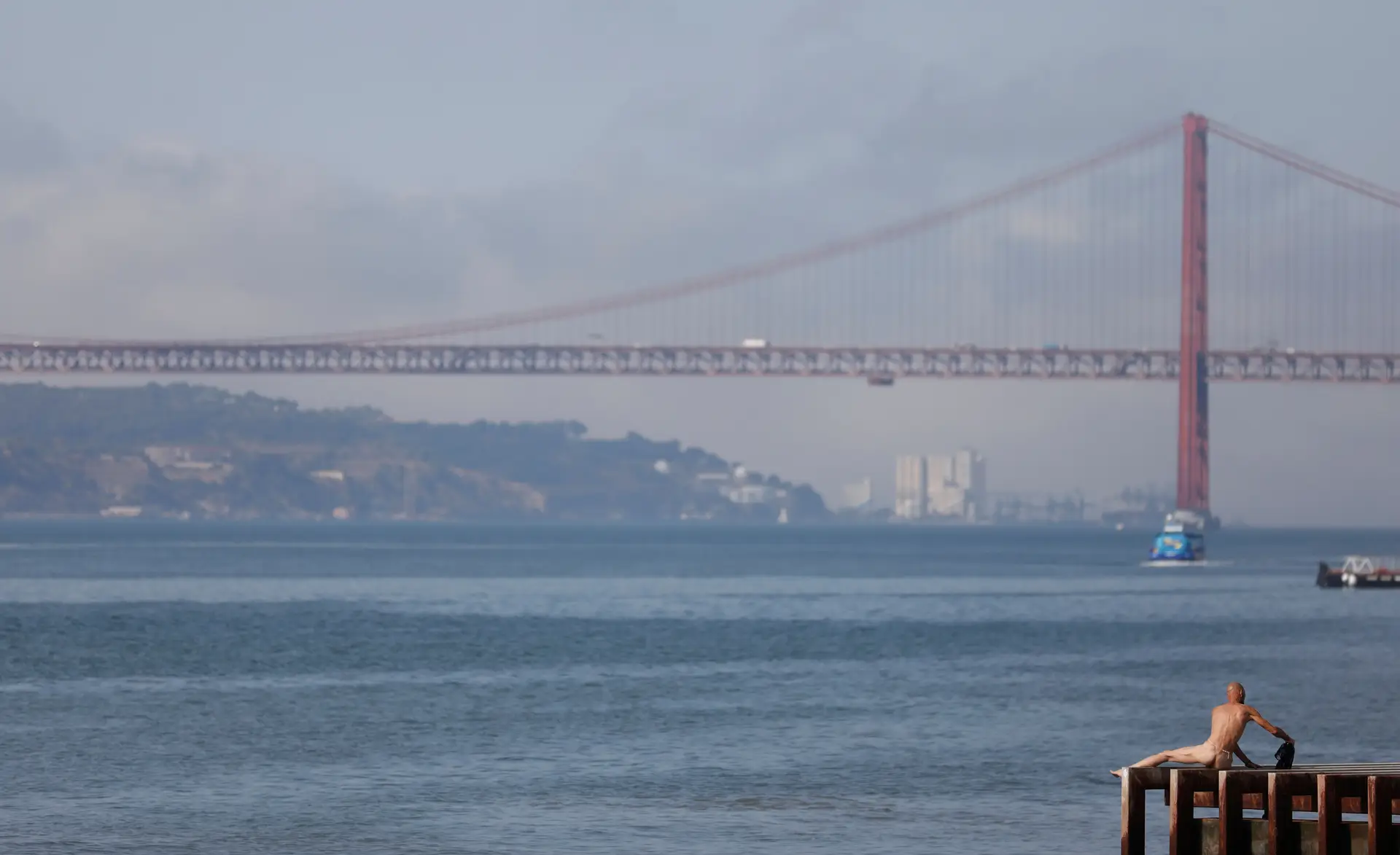 Um homem apanha sol junto ao Rio Tejo, em Lisboa.