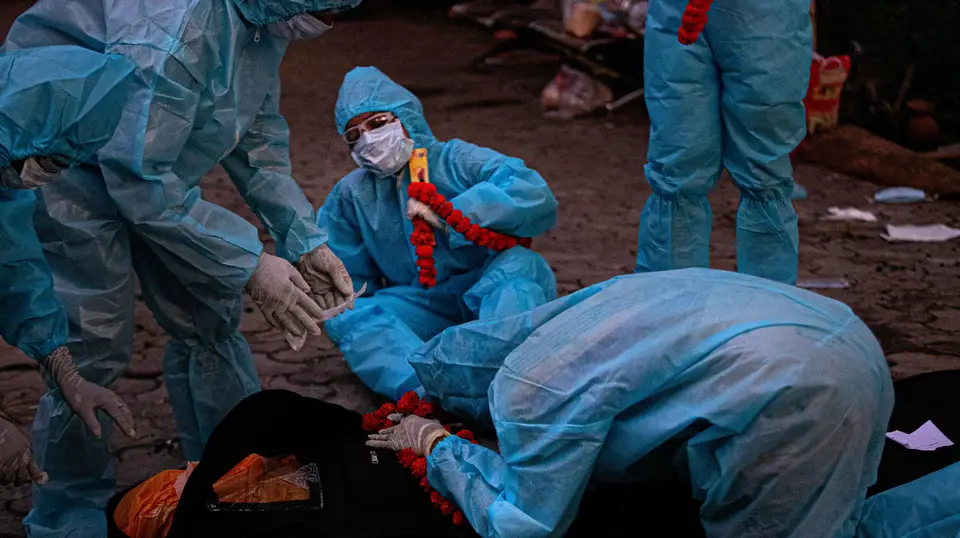 Familiares de um doente que morreu com covid-19 equipados com equipamento de proteção individual despedem-se do corpo, em Guwahati, na Índia.