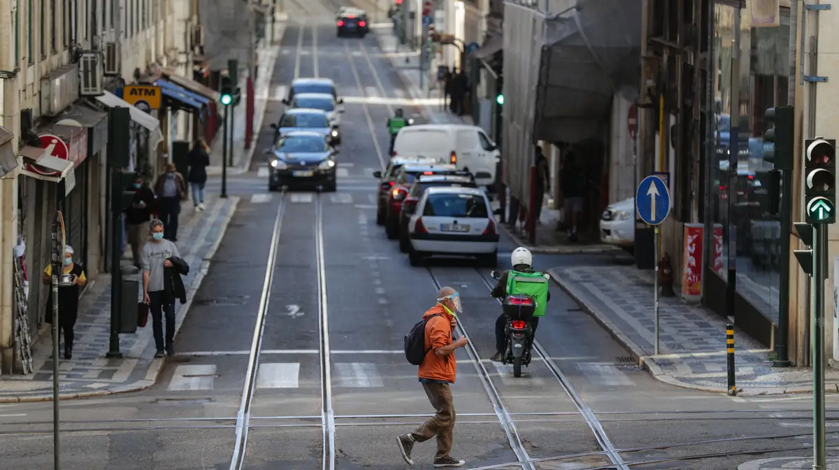 Um traseunte atravessa a rua na zona da baixa pombalina de Lisboa