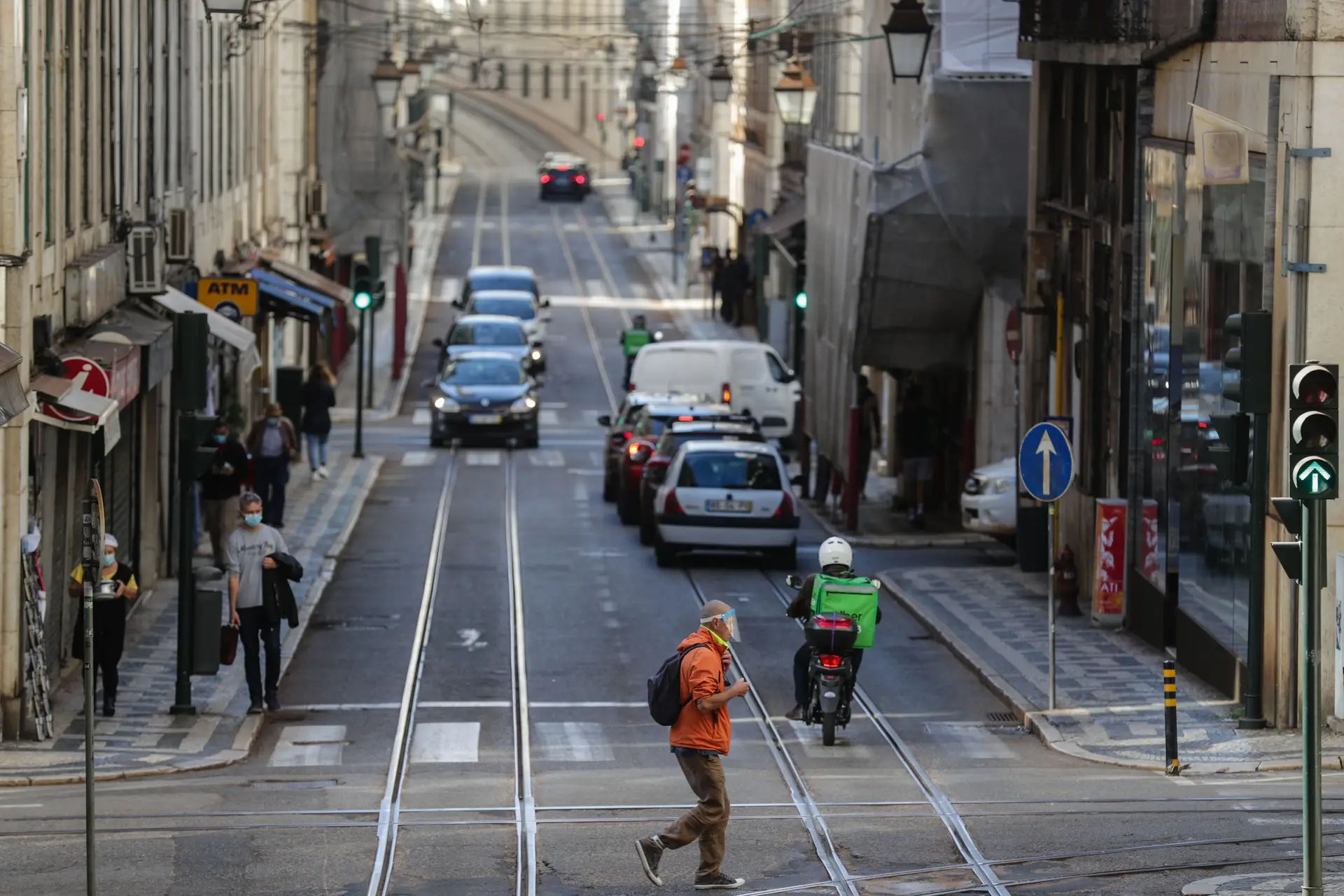 Um traseunte atravessa a rua na zona da baixa pombalina de Lisboa