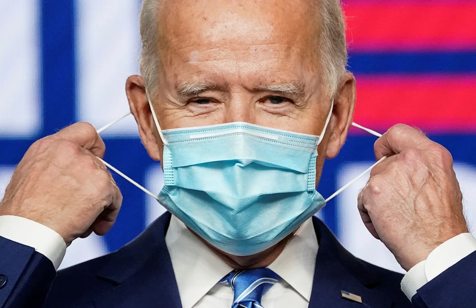 Joe Biden remove a sua máscara para discursar na noite das eleições presidenciais.