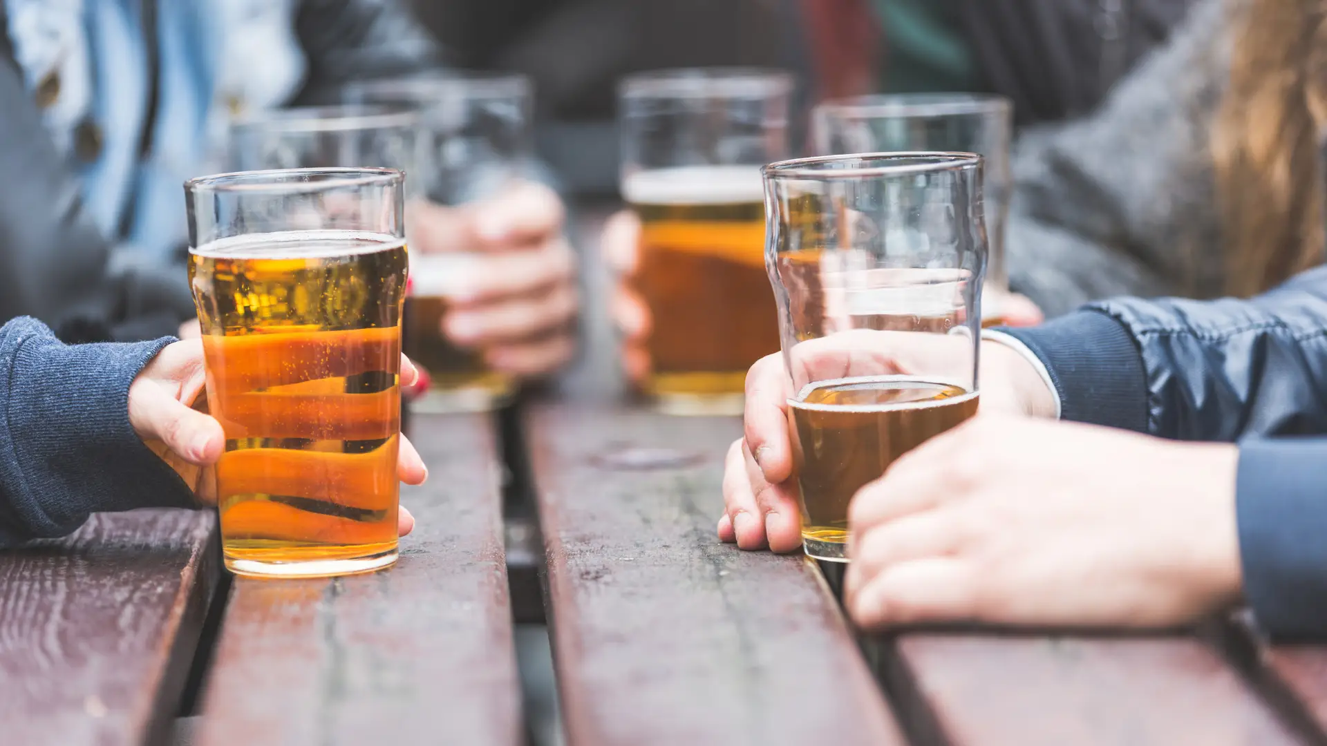 Mãos seguram copos de cerveja em Londres, Reino Unido