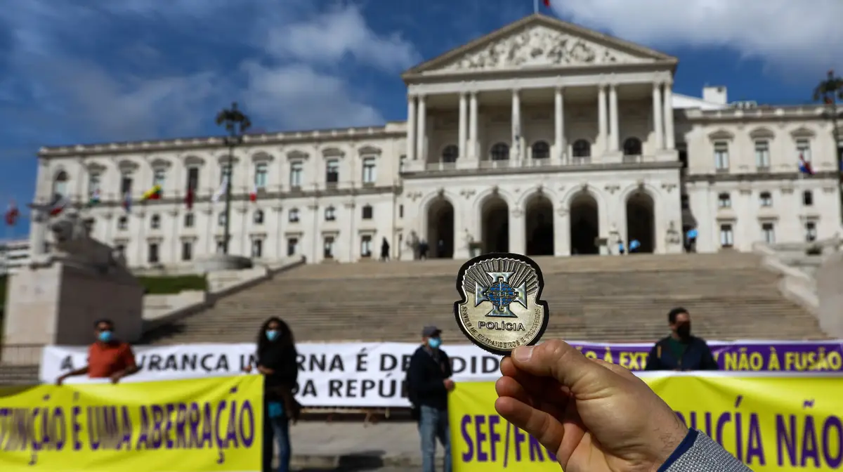 Um inspetor do Serviço de Estrangeiros e Fronteiras (SEF) apresenta o seu crachá durante a manifestação em frente da Assembleia da República, num protesto organizado pelo Sindicato da Carreira de Investigação e Fiscalização do Serviço de Estrangeiros e Fronteiras contra a intenção do Governo de extinguir o serviço, em Lisboa
