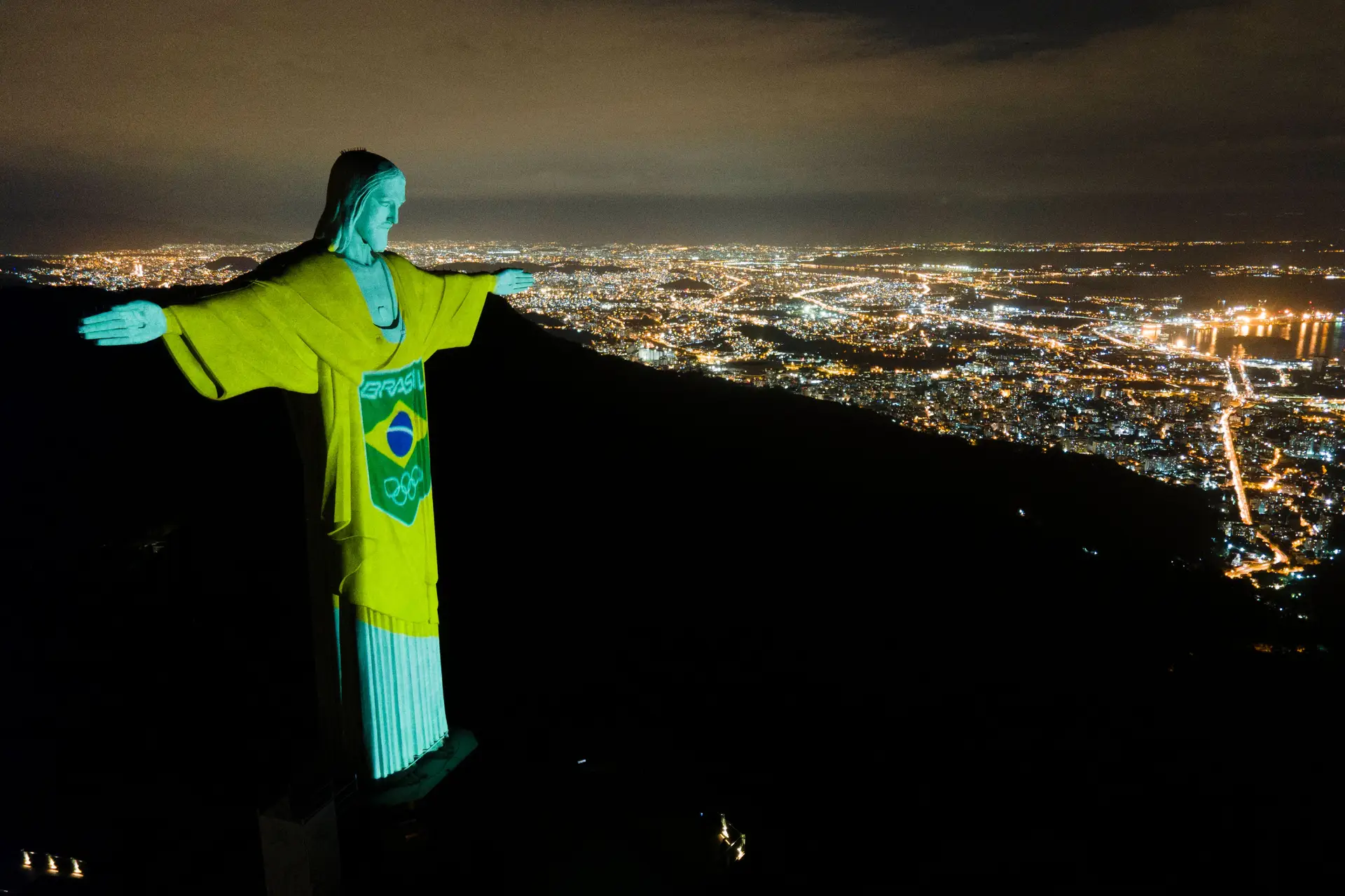 Imagem da bandeira da seleção olímpica do Brasil projetada na estátua do Cristo Redentor, no Rio de Janeiro. Uma iniciativa do Comité Olímpico Brasileiro que pretende realçar a importância do desporto na luta contra a covid-19, numa altura em faltam cem dias para o arranque dos Jogos Olímpicos de Tóquio.