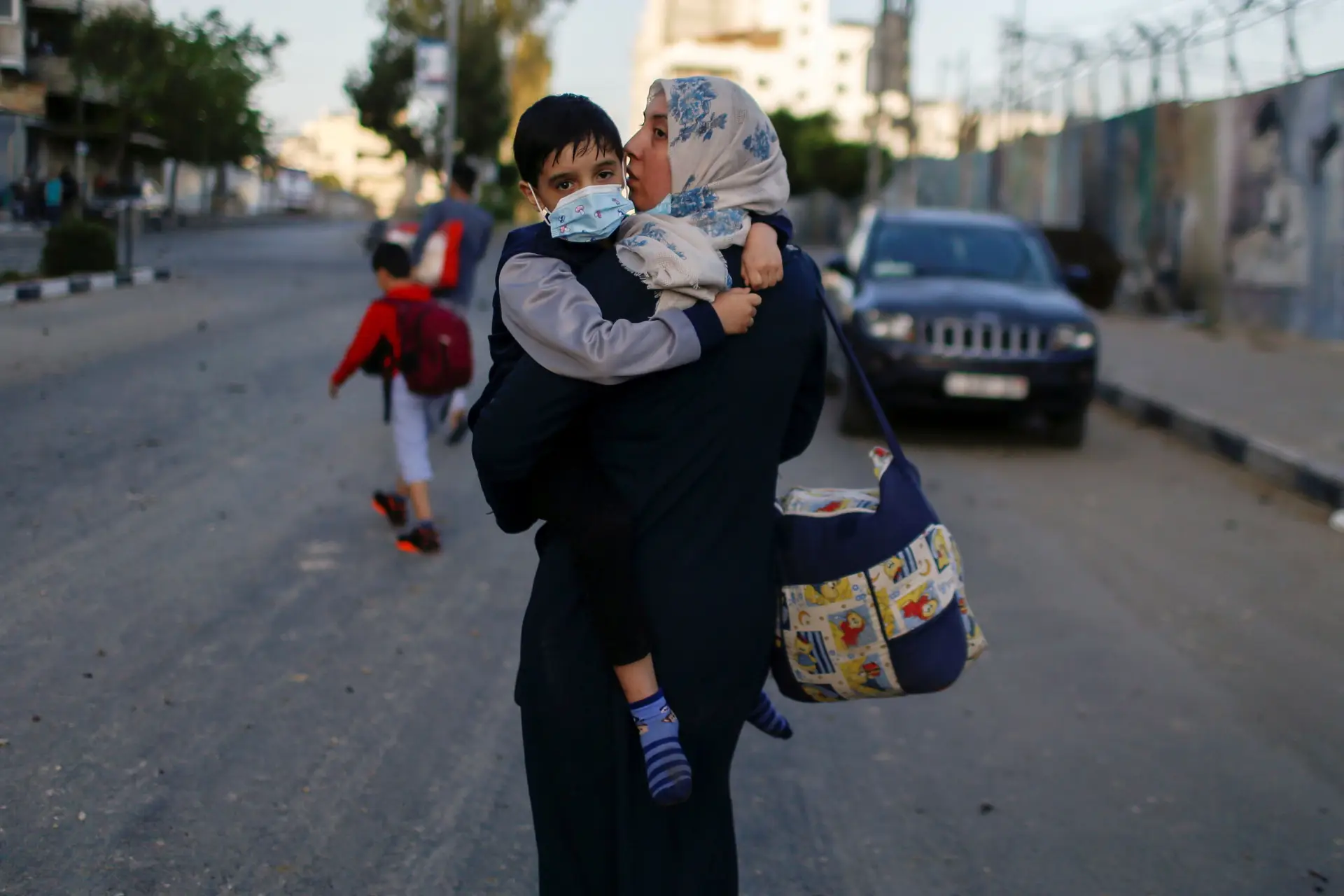 Uma mulher palestiniana foge com o filho depois do prédio onde moram ter sido atingido por um bombardeamento aéreo israelita, esta quarta-feira, em Gaza.
