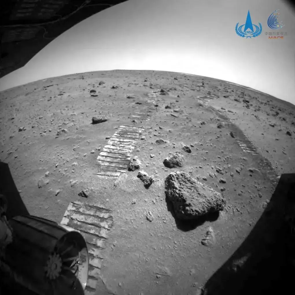 O rover chinês em Marte, Zhurong, já percorreu 808 metros no acidentado terreno marciano: uma área repleta de rochas, crateras e dunas. A foto foi tirada pela câmara traseira, pelo que é possível ver as marcas deixadas pelo veículo.