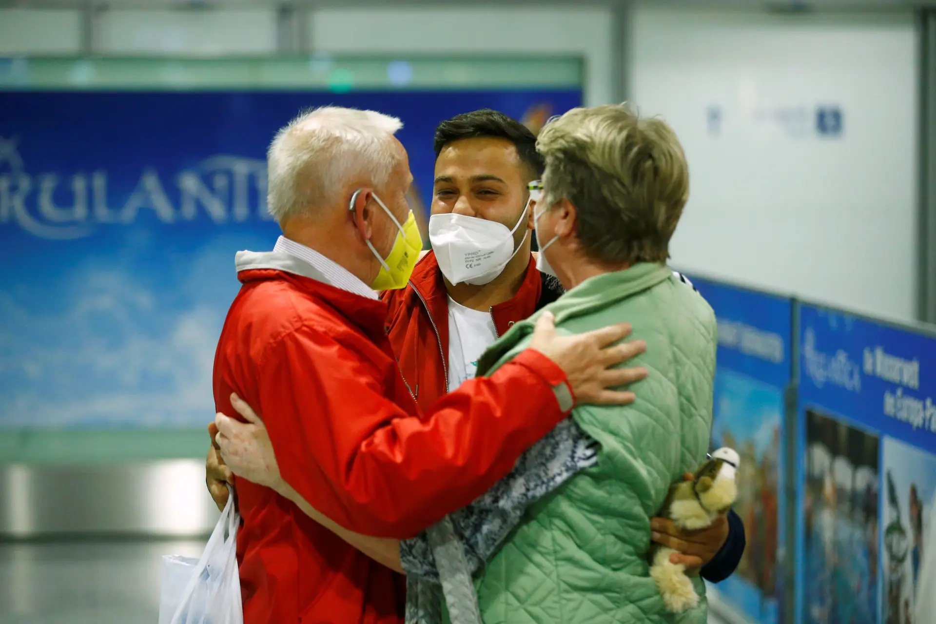 Um casal abraça um homem depois de desembarcar de um voo que transportava refugiados de Cabul, no Afeganistão, no aeroporto de Frankfurt, na Alemanha.