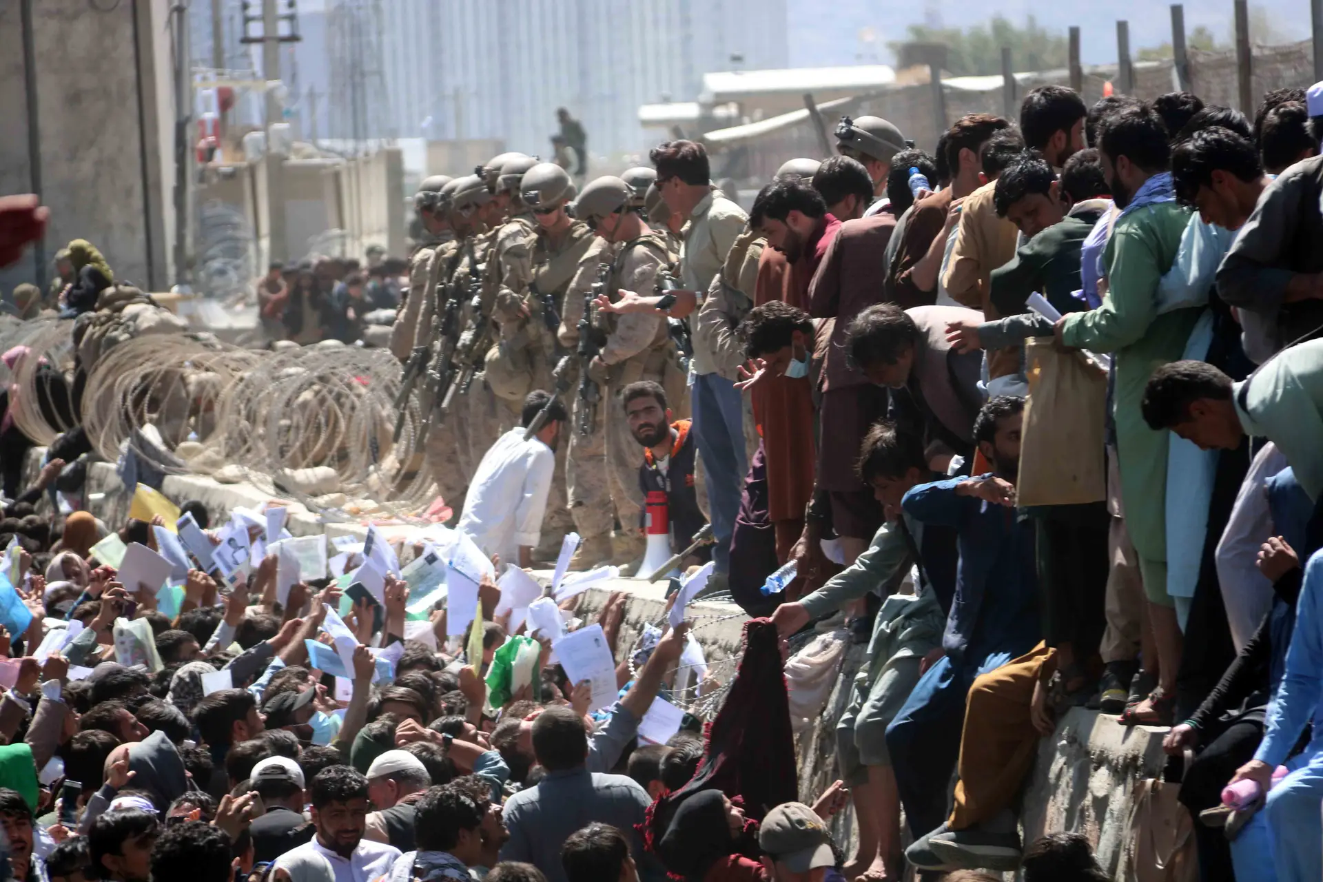 Afegãos tentam chegar às forças de segurança internacionais para mostrar as suas credenciais para fugir do país, junto ao aeroporto de em Cabul, Afeganistão