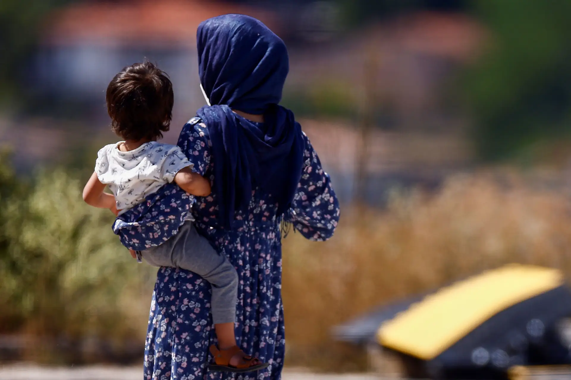 Cidadão afegã com um bebé ao colo no campo de refugiados da Cruz Vermelha, em Itália.