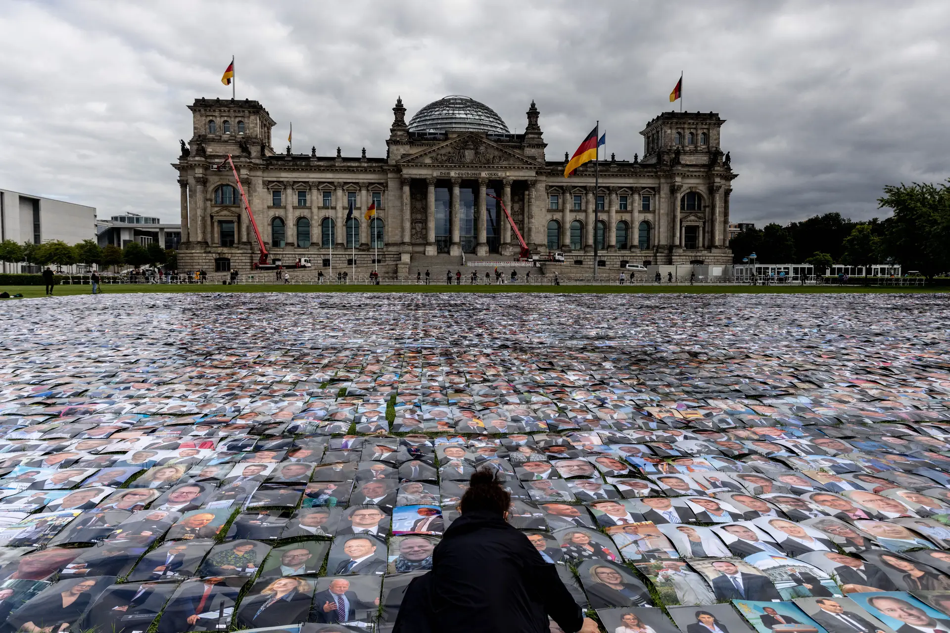Ativista dos direitos humanos coloca várias fotos de políticos alemães à frente do Palácio Reichstag, onde o Parlamento federal da Alemanha exerce as suas funções. O ato acontece durante um protesto contra violação dos direitos humanos.