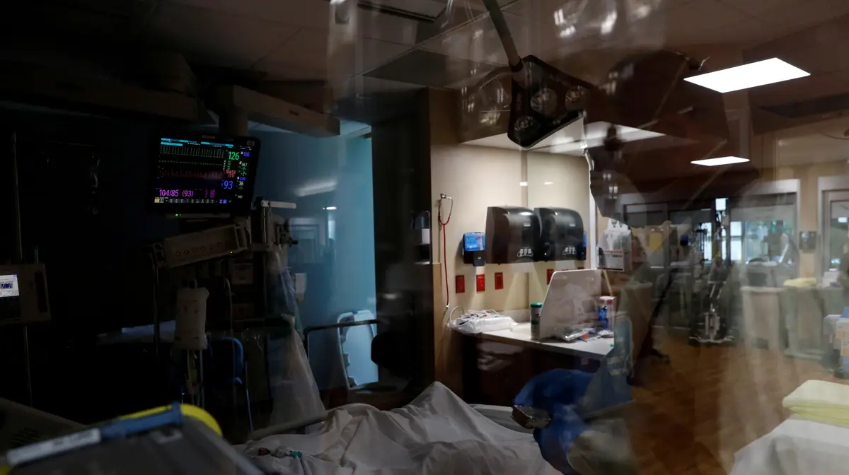 Um padre com uma bíblia numa sala de isolamento de um paciente com covid-19 nos cuidados intensivos, no Sarasota Memorial Hospital, em Sarasota, Flórida, EUA.