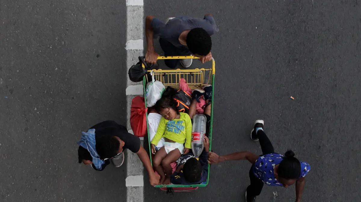 Migrantes que fazem parte de uma caravana que está a atravessar o México em direção aos Estados Unidos, transportam crianças adormecidas em carrinhos de compras.