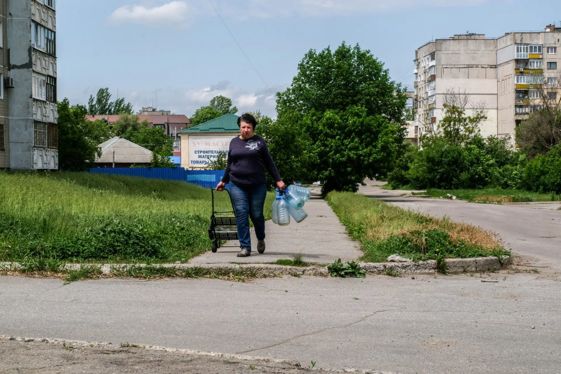 LYSYCHANSK, UKRAINE – 2022/05/28: A woman walks in an empty and deserted street of the city going to collect water. Lysychansk is a city on the high right bank of the Donets River in the Luhansk region. The city is part of a metropolitan area including Severodonetsk and Rubizhne; the three towns constitute one of Ukraine’s largest chemical complexes. Lysychansk is now the frontline since the Russian troops destroyed the bridge connecting Severodonetsk to Lysychansk. Russian troops are attacking the city and moving towards it. The Russian army occupies the main road that connects Lysychansk to Kramatorsk. (Photo by Rick Mave/SOPA Images/LightRocket via Getty Images)