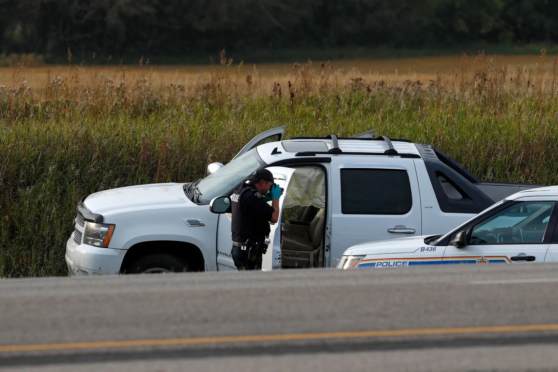 Agente da Real Polícia Montada Canadiana tira fotografias daa carrinha onde o suspeito, Myles Sanderson, foi preso, ao longo da autoestrada 11 perto da cidade de Rosthern, Saskatchewan, Canadá.