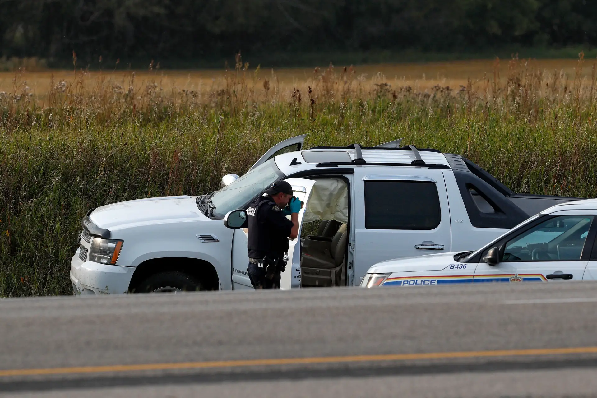Agente da Real Polícia Montada Canadiana tira fotografias daa carrinha onde o suspeito, Myles Sanderson, foi preso, ao longo da autoestrada 11 perto da cidade de Rosthern, Saskatchewan, Canadá.