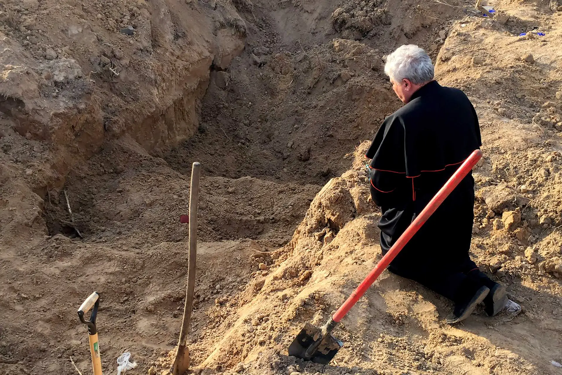 O Cardeal Konrad Krajewski reza no local de uma vala comum nas proximidades de Borodyanka, Ucrânia, na Sexta-feira Santa em 15 de abril de 2022 