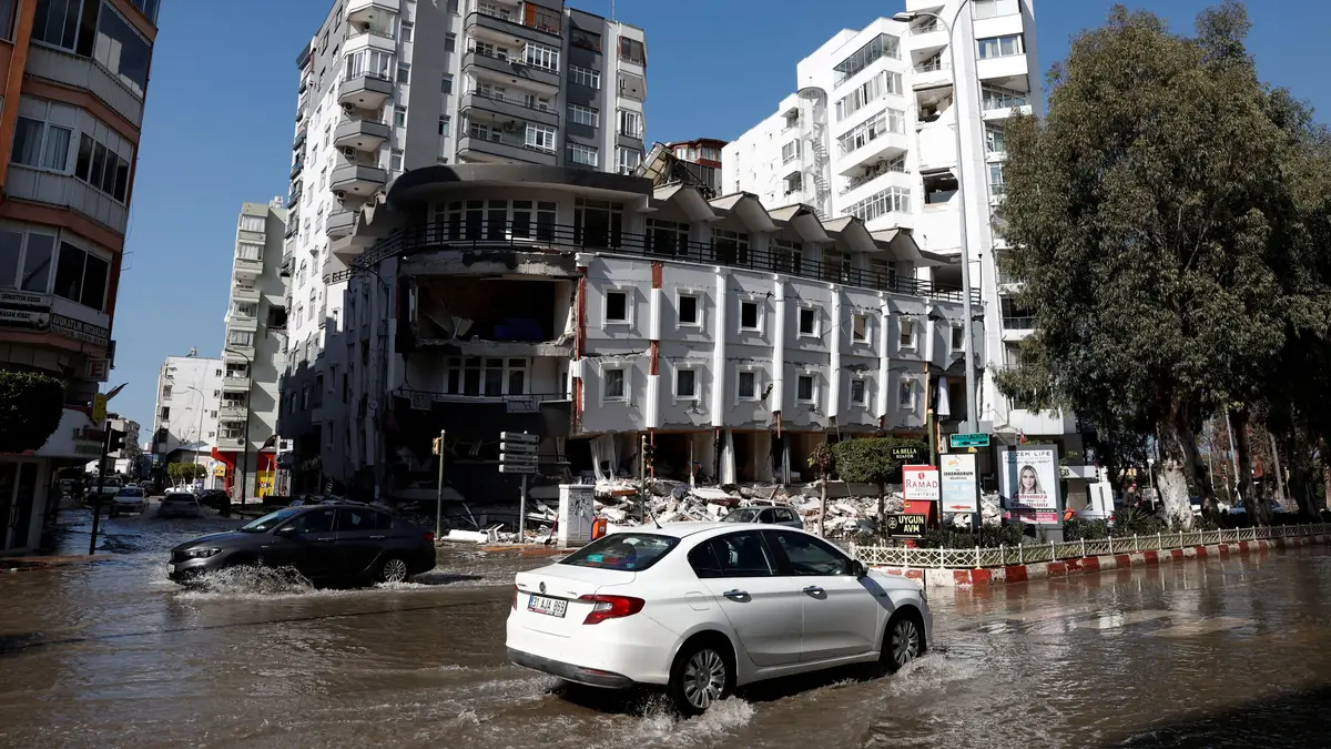 Os automóveis circulam numa rua inundada pela água do mar, numa estrada costeira, após terramoto em Iskenderun, Turquia.