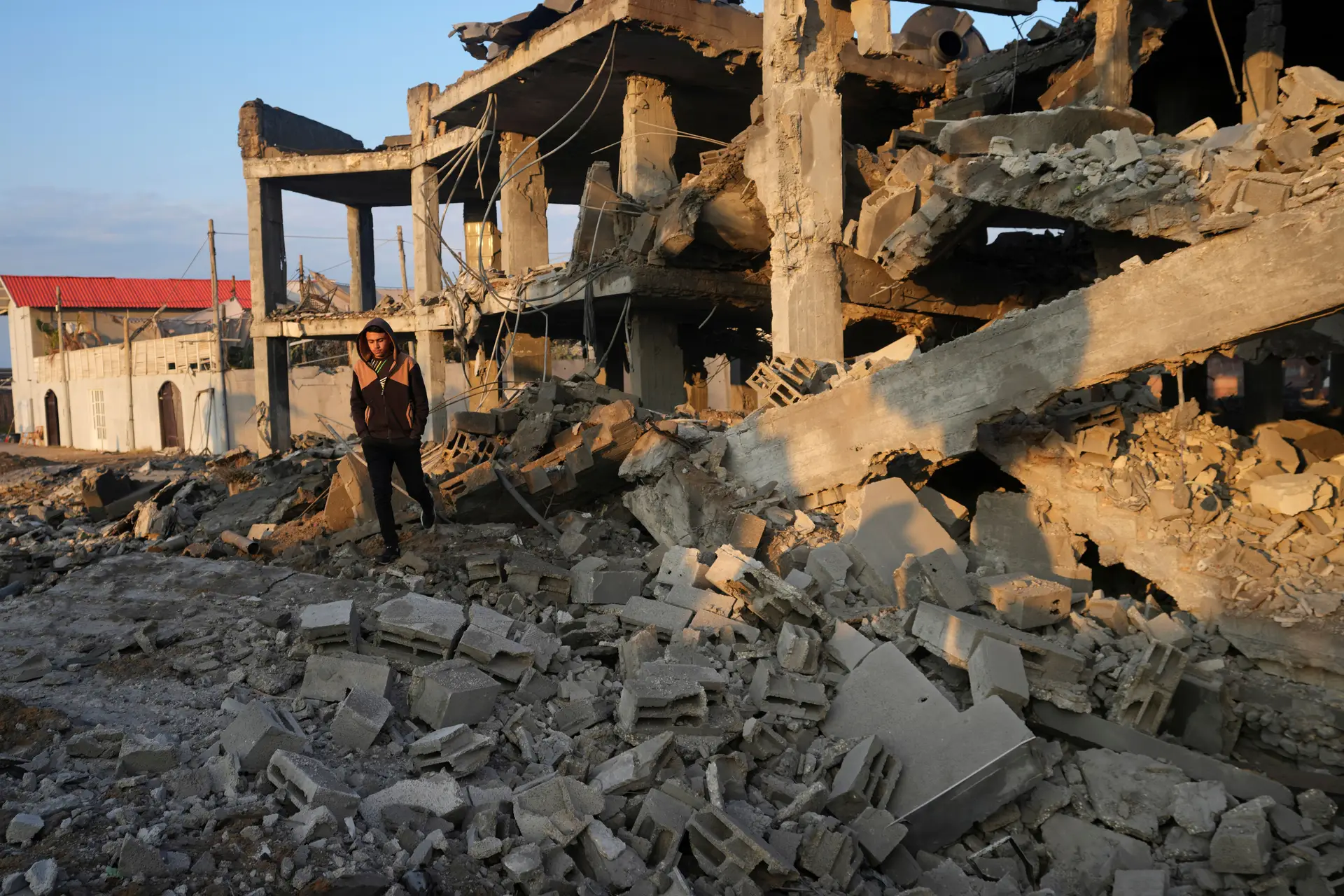 Um jovem atravessa os escombros de um edifício atingido por ataques aéreos israelitas na cidade de Gaza.