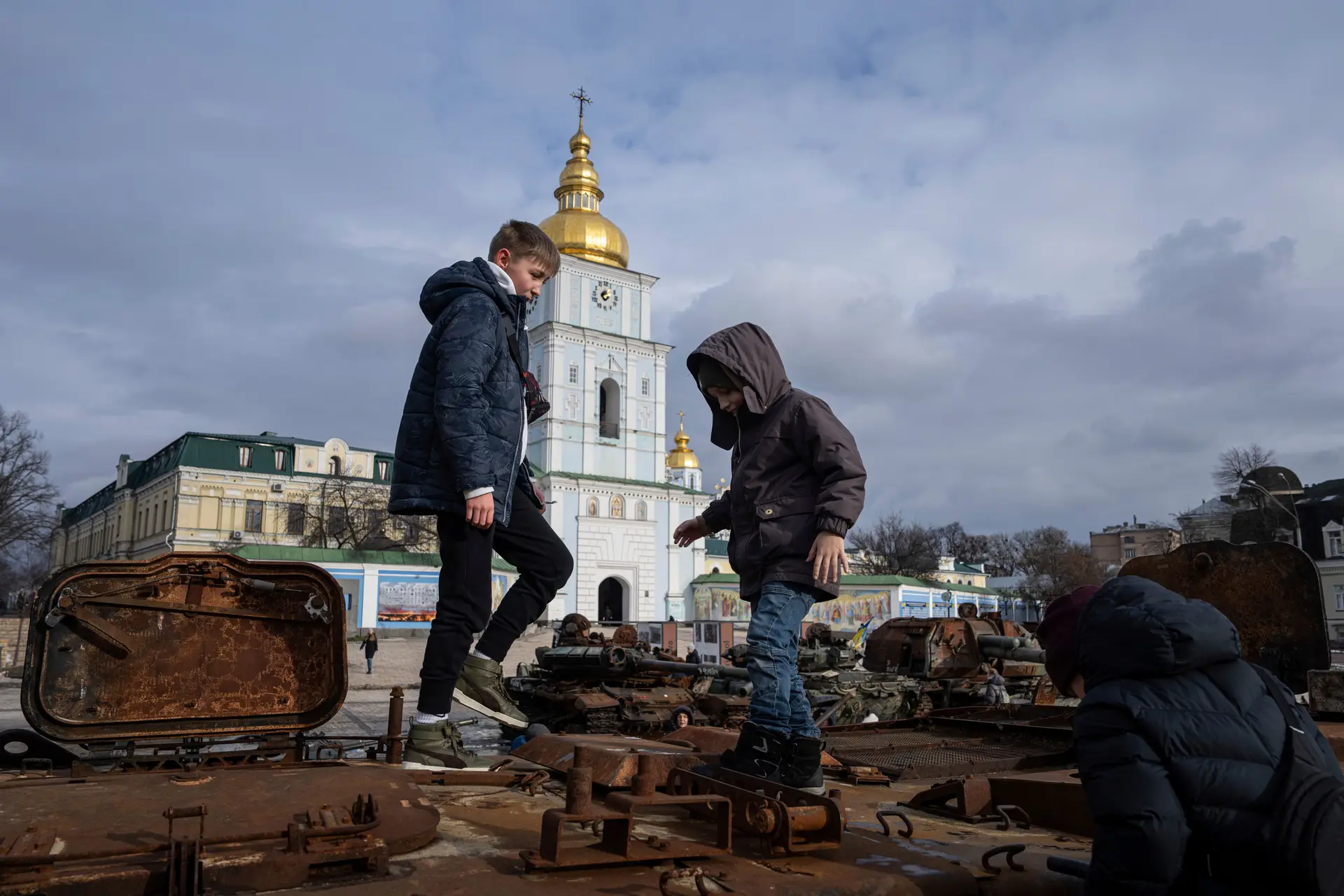 Crianças brincam junto a o que resta de um veículo militar russo no centro de Kiev, capital da Ucrânia.
