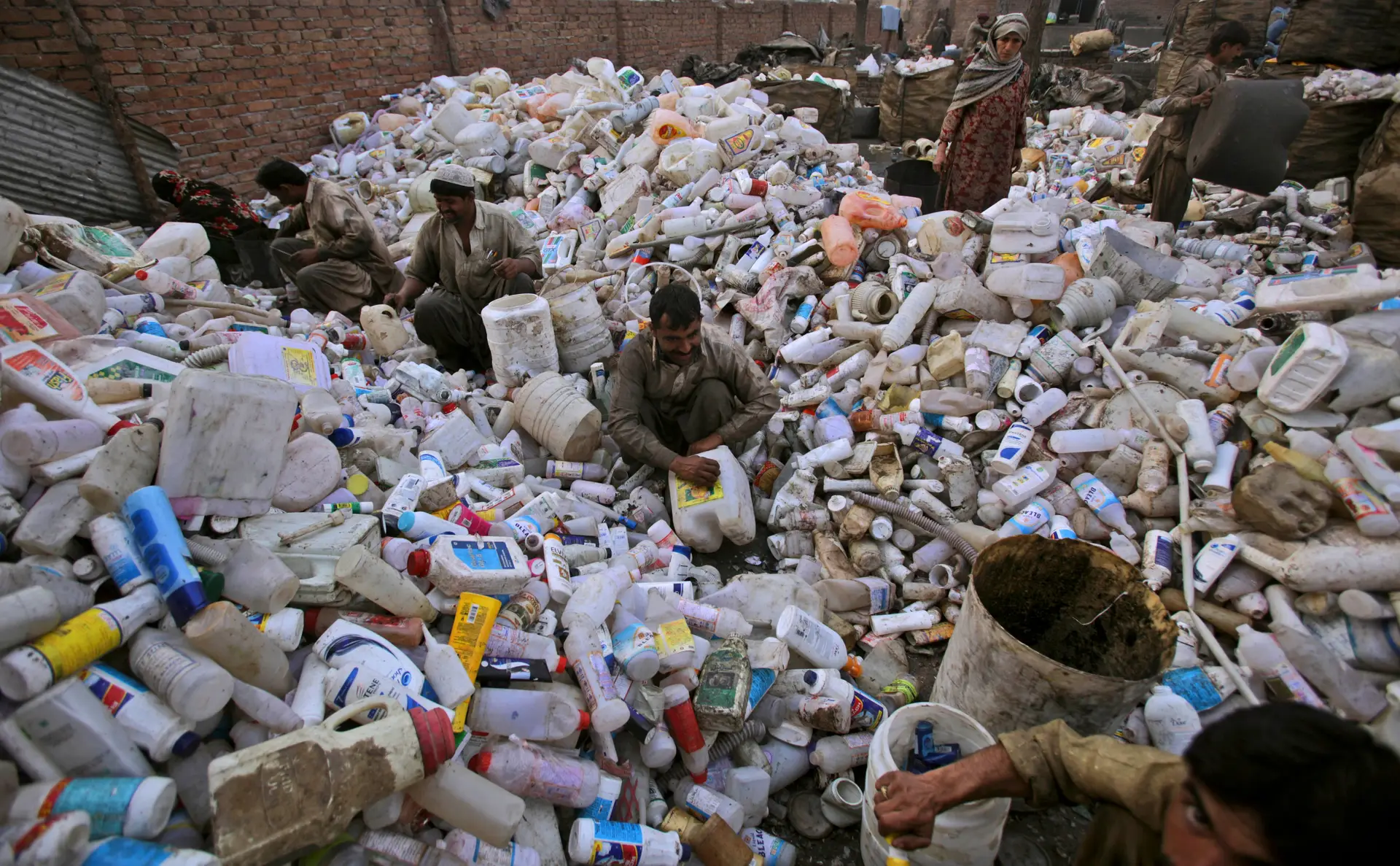 Homens e mulheres paquistaneses trabalham em uma fábrica de reciclagem de plástico nos arredores de Islamabad