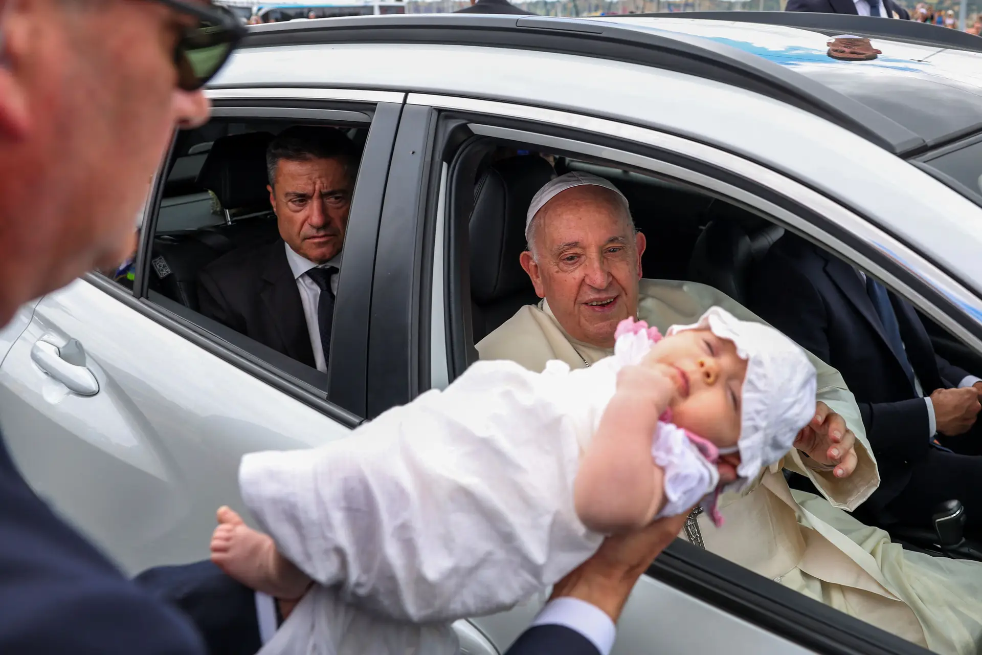 Francisco beijou e abençoou vários bebés nas primeiras horas em Lisboa, com elementos do corpo de segurança a levar as crianças junto do carro