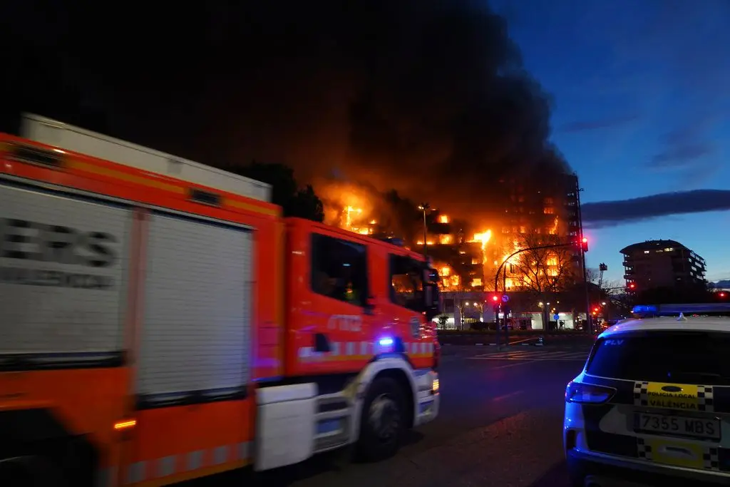 Um carro de bombeiros e um carro da polícia à porta do bloco habitacional em chamas em Valência, Espanha