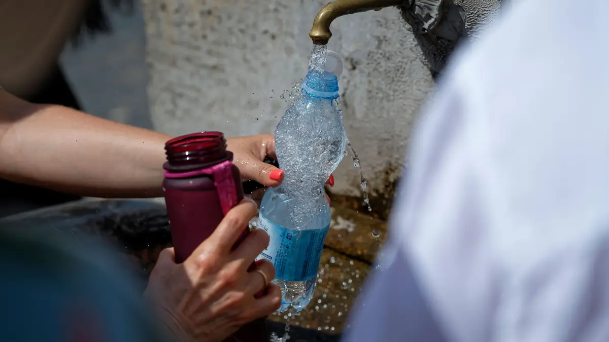 Pessoas enchem as garrafas de água num dia de calor