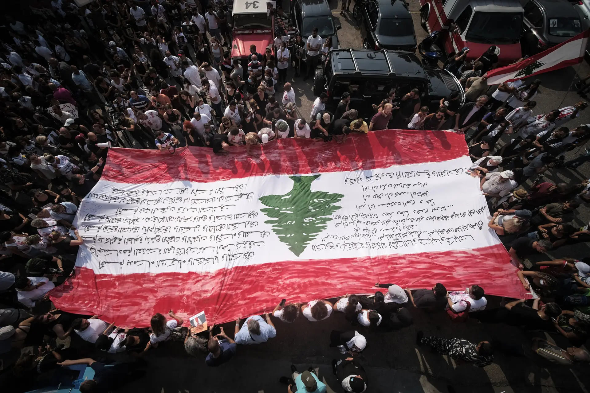 Cidadãos carregam a bandeira libanesa no quartel de bombeiros de Karantina, numa homenagem às vítimas da explosão do porto de Beirute. (4 de Agosto de 2022)