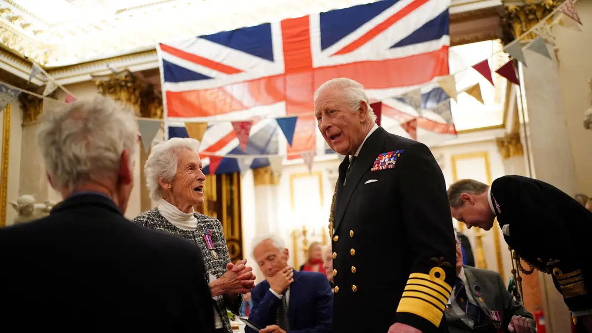O rei Carlos III junta-se aos veteranos da Segunda Guerra Mundial num chá no Palácio de Buckingham, no centro de Londres, após o cortejo militar para assinalar o 80.º aniversário do Dia da Vitória, a 5 de maio de 2025. 