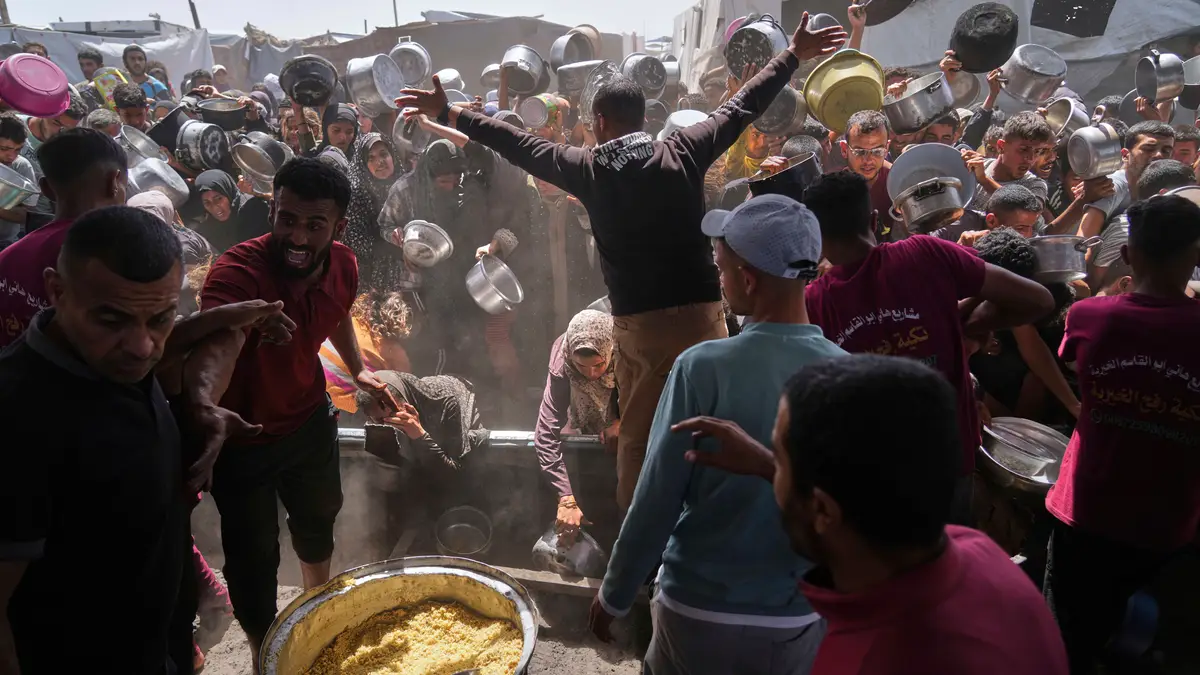 Palestinianos lutam para obter alimentos doados numa cozinha comunitária em Khan Younis, Faixa de Gaza, sexta-feira, 16 de maio de 2025. 