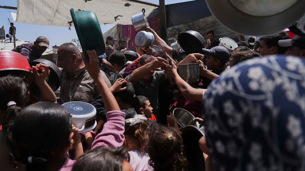 Palestinianos lutam para obter alimentos doados numa cozinha comunitária em Jabalia, no norte da Faixa de Gaza, segunda-feira, 19 de maio de 2025.