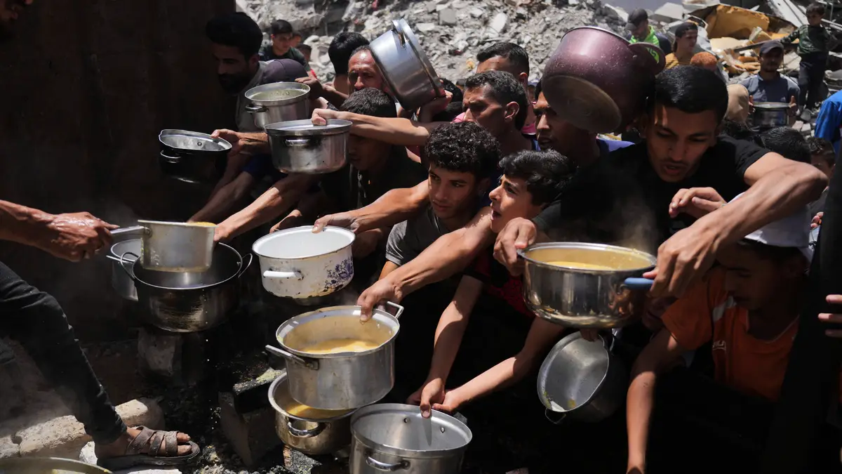 Palestinianos lutam para obter alimentos doados numa cozinha comunitária em Jabalia, no norte da Faixa de Gaza, segunda-feira, 19 de maio de 2025.