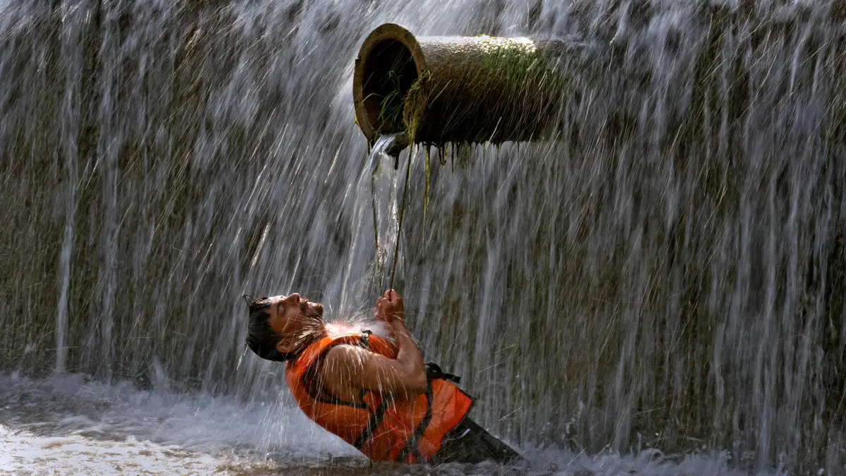 Um paquistanês refresca-se num riacho quando as temperaturas atingem os 39 graus Celsius em Islamabad, Paquistão, sexta-feira, 24 de maio de 2024.