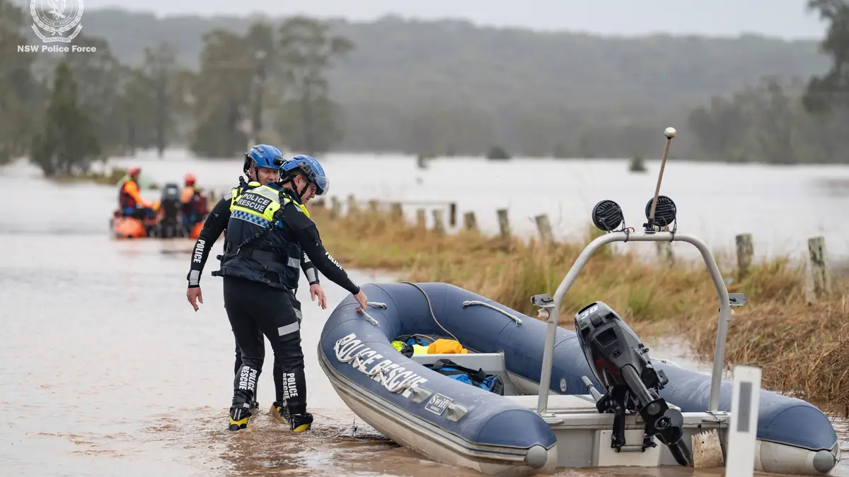 Trabalhadores de emergência percorrem as águas das cheias enquanto preparam barcos insufláveis para efetuar salvamentos perto de Taree, Austrália, quinta-feira, 22 de maio de 2025. 