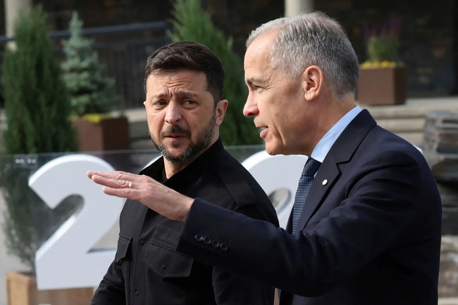 O Primeiro-Ministro do Canadá, Mark Carney (à direita), caminha com o Presidente da Ucrânia, Volodymyr Zelenskyy, durante a Cimeira de Líderes do G7 em Kananaskis, Alberta, Canadá, na terça-feira, 17 de junho de 2025.