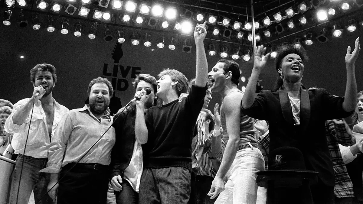 Da esquerda para a direita, George Michael dos Wham!, o promotor do concerto Harvey Goldsmith, Bono dos U2, Paul McCartney, o organizador do concerto Bob Geldof e Freddie Mercury dos Queen juntam-se no final do concerto Live Aid de solidariedade contra a fome, no Estádio de Wembley, Londres, 13 de julho de 1985.