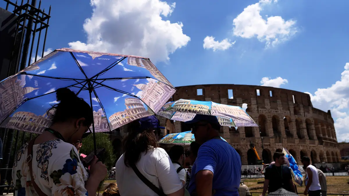 Turistas usam guarda-sóis para se proteger do calor enquanto fazem fila para uma visita ao Fórum, em Roma, na terça-feira, 22 de julho de 2025.
