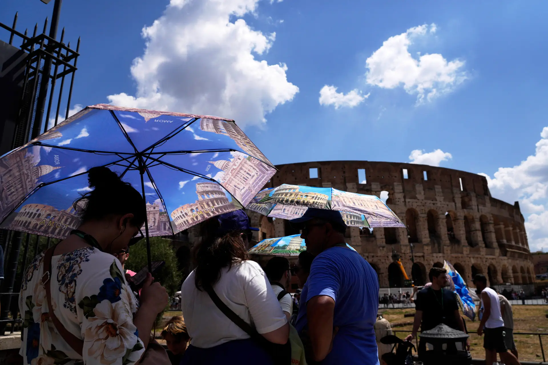 Turistas usam guarda-sóis para se proteger do calor enquanto fazem fila para uma visita ao Fórum, em Roma, na terça-feira, 22 de julho de 2025.