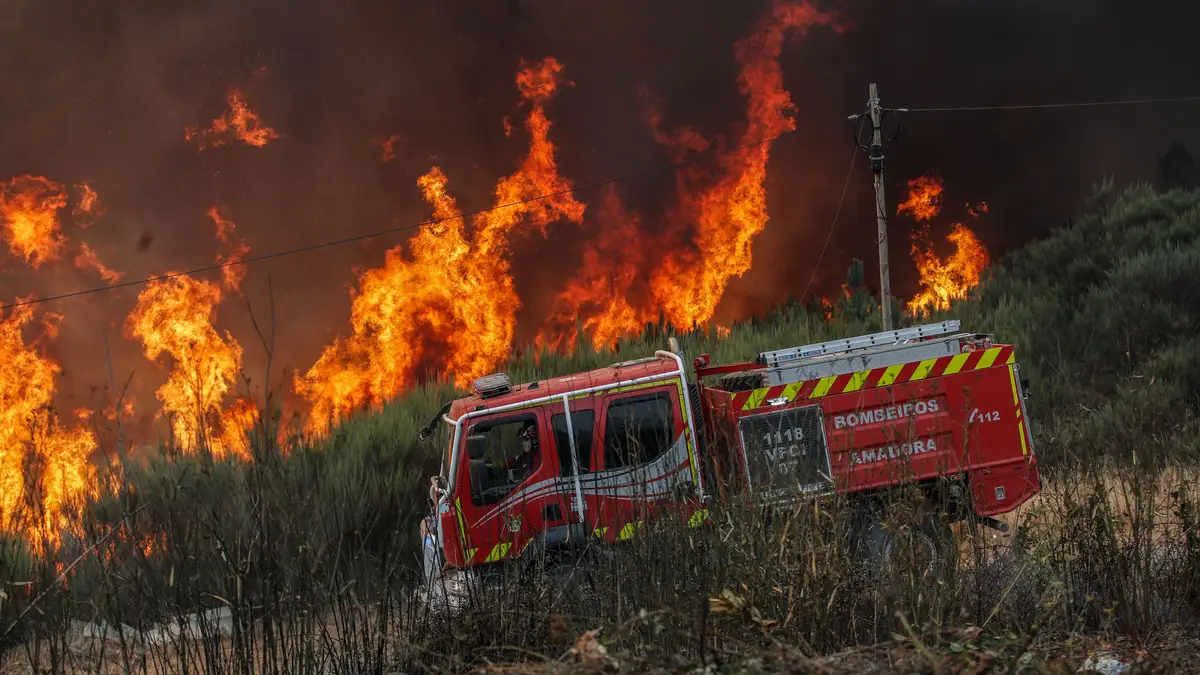 Bombeiros combatem as chamas durante o incêndio na encosta da aldeia de Moura da Serra, Arganil, 14 de agosto de 2025.