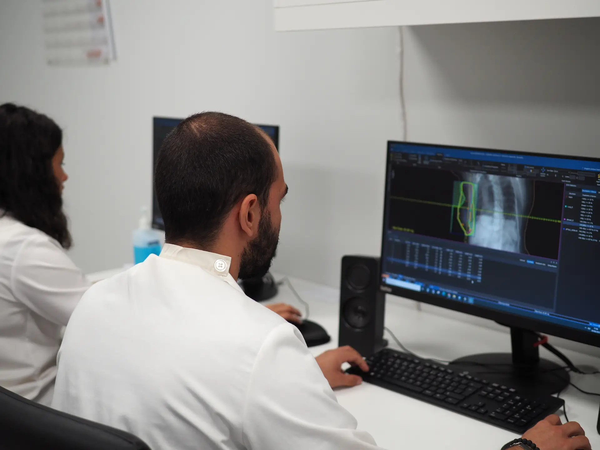 Nos bastidores, uma equipa de profissionais garante a segurança e execução do tratamento. (da esq. para a dir. : Mariana Girão, física médica, e Anthony Ribeiro, técnico dosimetrista)