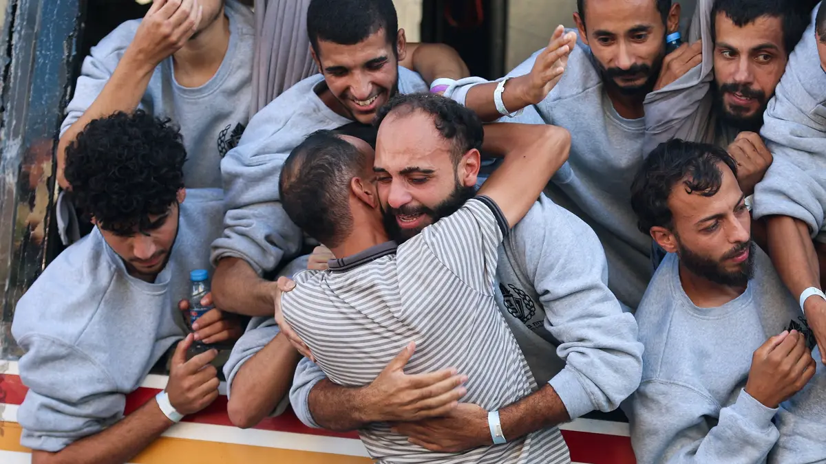 Um prisioneiro palestiniano libertado por Israel, no âmbito da troca de reféns e prisioneiros e do acordo de cessar-fogo entre o Hamas e Israel, abraça um homem em Khan Younis, no sul da Faixa de Gaza, a 13 de outubro de 2025.