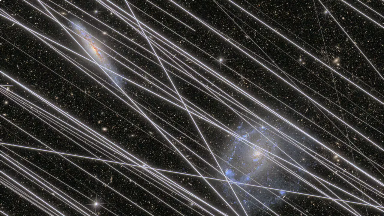 Simulação da contaminação projetada por satélites num dos futuros telescópios espaciais. As faixas de luz refletidas pelos satélites artificiais de telecomunicações ofuscam a imagem de duas galáxias a interagir em segundo plano.